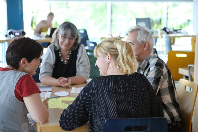 Die Teilnehmerinnen und Teilnehmer arbeiten am Tisch zusammen.