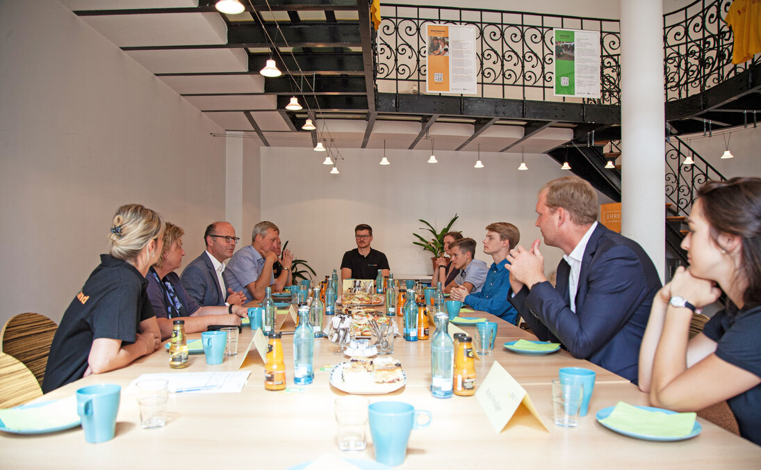 Männer und Frauen sitzen an einem Tisch.